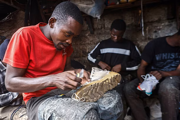 A local artisan repairs a pair of worn shoes, helping extend their life and offering a more affordable alternative to buying a new pair.