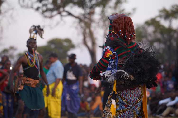 Makishi performers emerge in elaborate masks and costumes, embodying ancestral spirits whose presence connects the living community to generations past. (Image by Justine Kunda for Nkwazi Magazine).