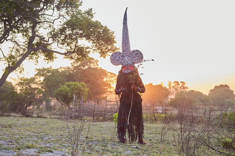 Likishi Chikuza attains total perfection in his duties. With his long conical mitre, his main function is to teach tundanji the art of the  kuhunga dance,  until perfected. (Image by Nkwazi/Justine Kunda).